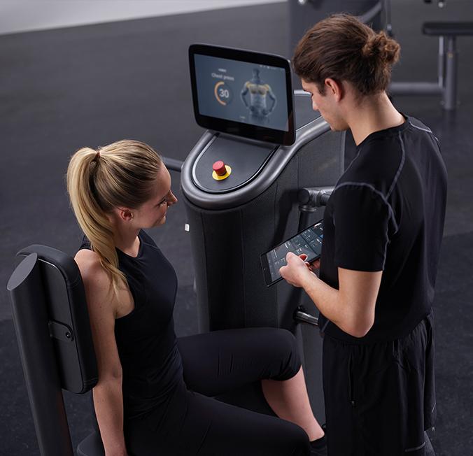 EGYM manufacturer image of a trainer guiding a member through the equipment